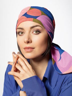 Vrouw draagt een chemo hoofddoekje met een vrolijke print