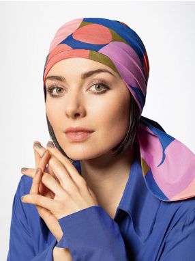Vrouw draagt een chemo hoofddoekje met een vrolijke print